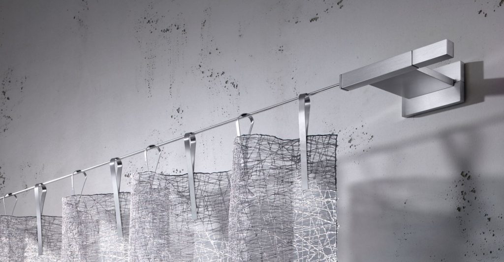 Detail einer Seilzug-Garnitur mit einem eleganten, transparenten und silbrig schimmernden Vorhang. Foto von Interstil.