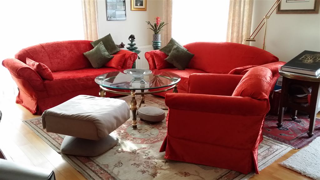 Klassisches Wohnzimmer mit Sofas und Sessel, die mit leuchtend roten neuen Hussen bezogen wurden. Foto aus dem Raumkonzept-Archiv.